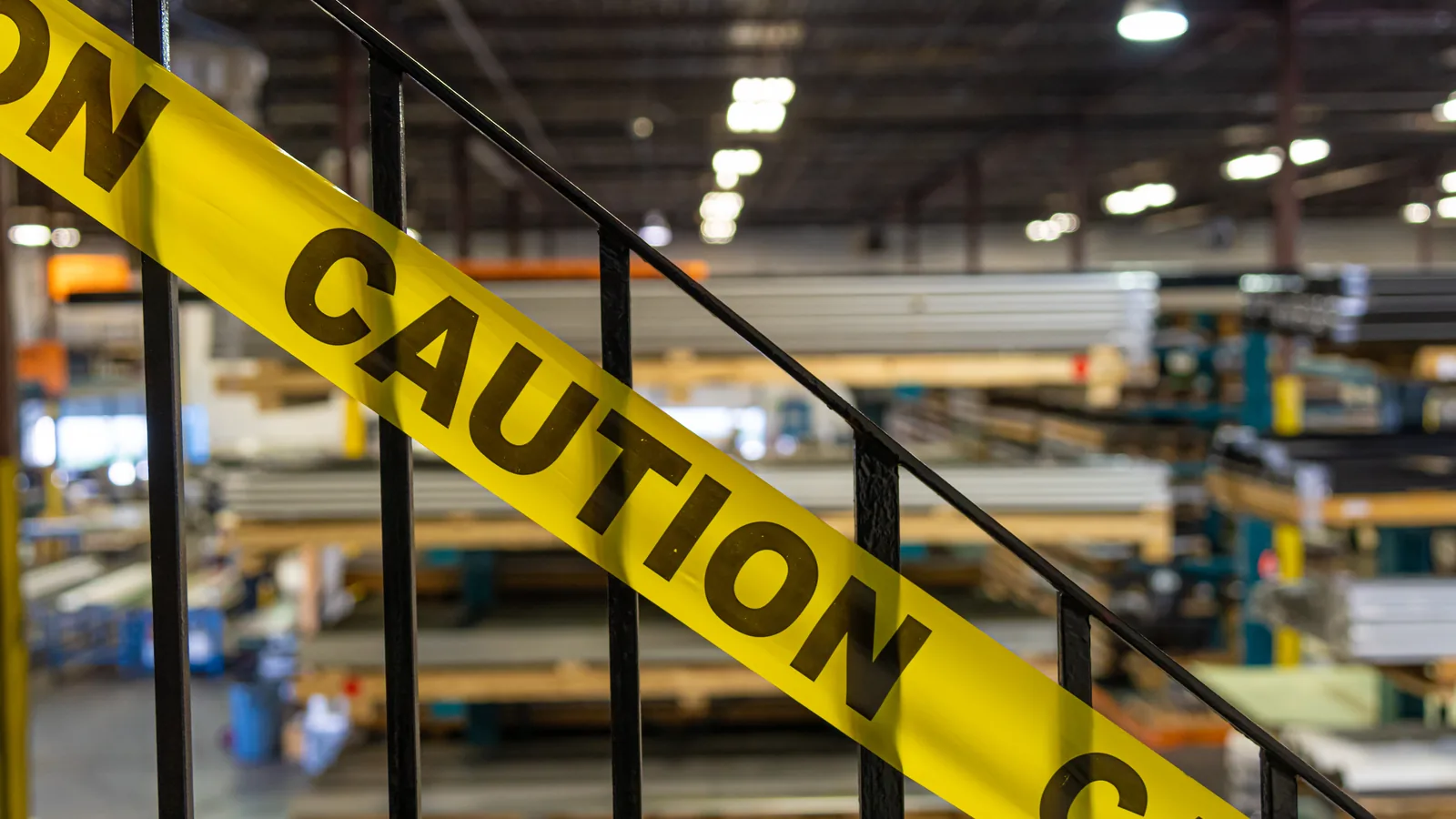 Yellow caution tape across an industrial facility stair railing